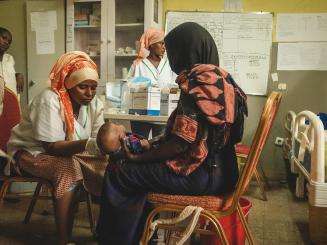 MSF aid worker treats child on mother's lap in Ethiopia during nutritional crisis in Afar region