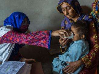 An MSF staff member treats a child carried by their mother in Pakistan after the floods.
