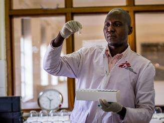 An MSF doctor holds up a test tube he is examining in a lab in Arua, Uganda.