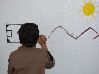 A child draws a sun and mountains on the wall during an art therapy session in Al-Hol camp, northeast Syria.