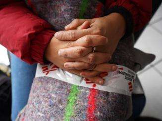 A migrant woman's hands folded on her lap