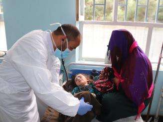An MSF doctor, Mohammad Qahir Poya checks the vital signs of three-year-old Zainat who was admitted to the measles in the measles isolation ward at Mazar-i-Sharif Regional Hospital, supported by MSF in Afghanistan.