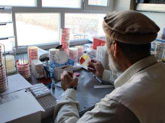 Dr Wardak Abdul Qayoum observes a culture plate to find an interesting bacterial strain in the laboratory in Boost Hospital, Lashkar Gah, Helmand, Afghanistan. 